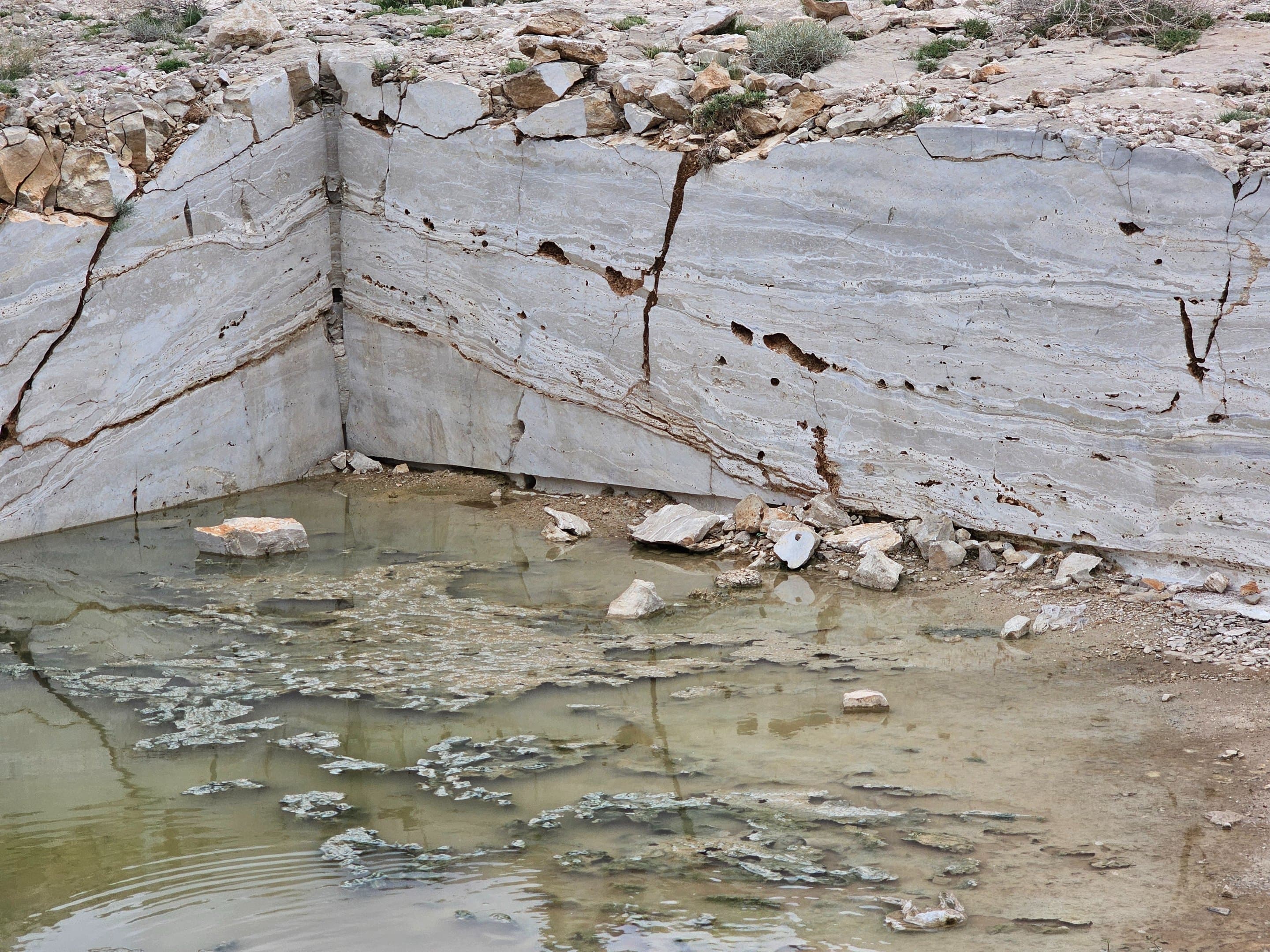 Large travertine block stack with quarry crane machinery in the background