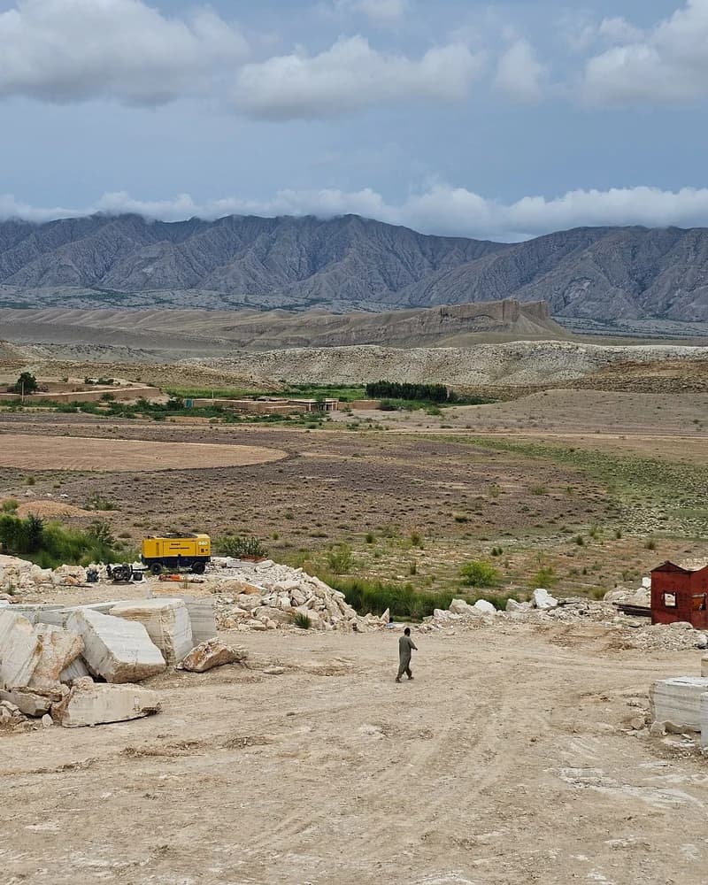 Quarry yard in Loralai with freshly cut travertine blocks awaiting transport, mountains in the background